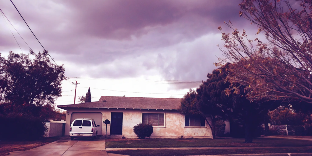 House with overcast sky and moving van.