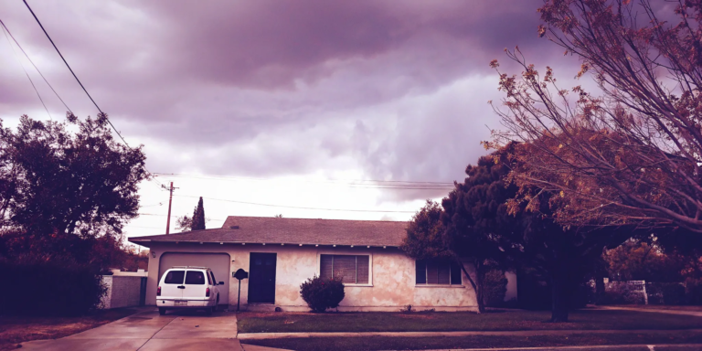 House with overcast sky and moving van.