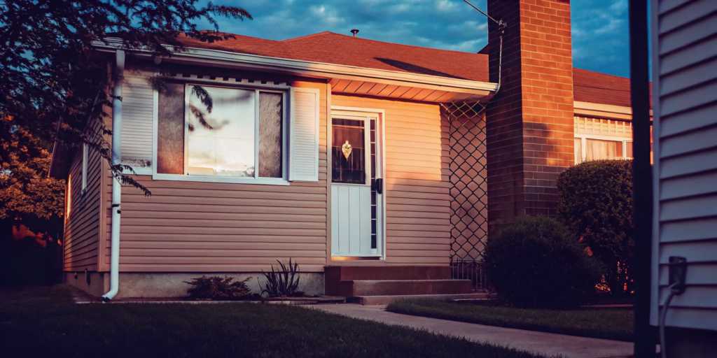 Beige house with white door for sale as is.
