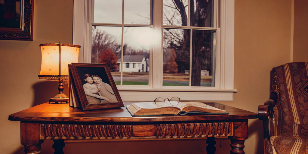 Inherited property: Family photo, book, and glasses on table by window.