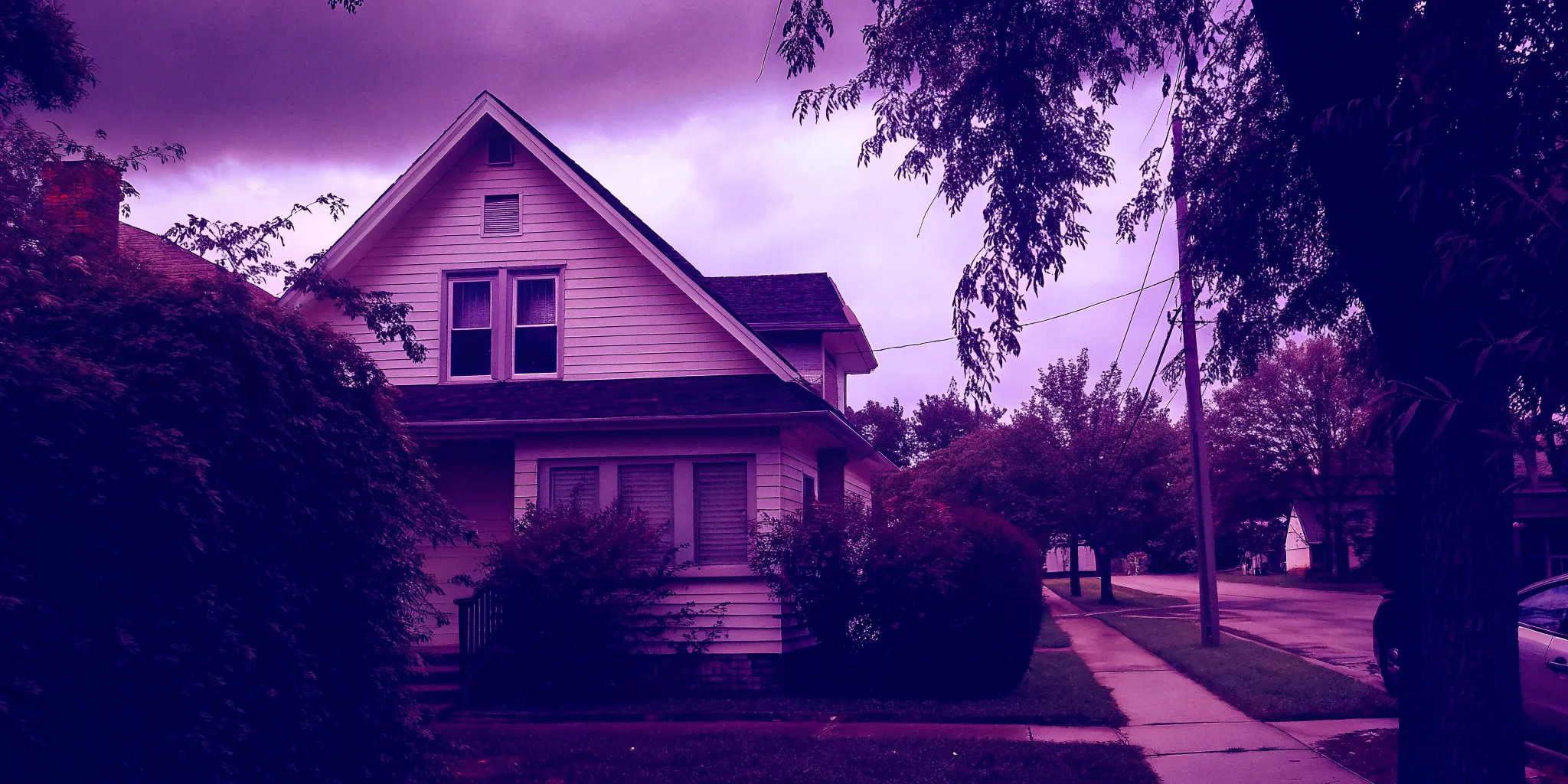 Overgrown bushes in front of a house for sale as is.