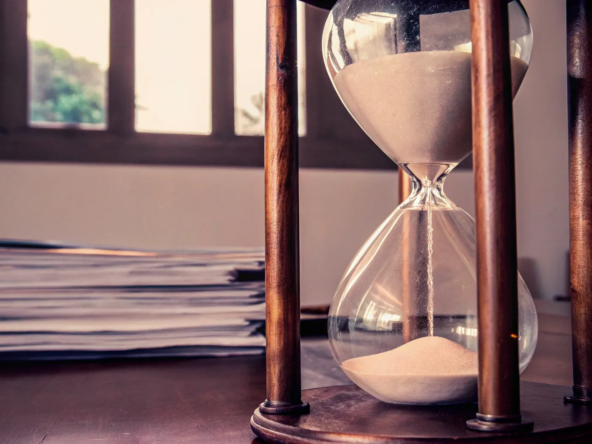 An hourglass and legal paperwork on a desk showing how long a probate sale takes.