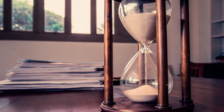 An hourglass and legal paperwork on a desk showing how long a probate sale takes.