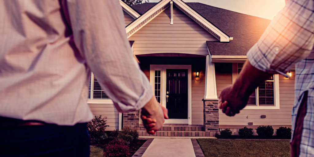 Couple holding hands in front of their new home, discussing closing costs for a private sale.