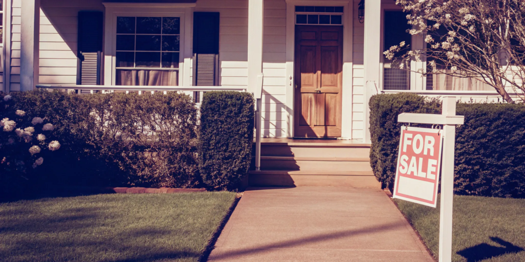 A house with a for sale sign, a crucial step in how to sell a house before foreclosure.