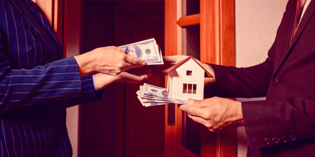 A person exchanges a house model for a stack of cash in an instant cash for home sale.